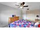 Clean bedroom with ceiling fan, wooden dresser, and a bright quilt at 15237 N 61St Dr, Glendale, AZ 85306