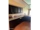 A kitchen showcases dark cabinets, granite countertops, and a stainless steel sink with wood-look tile flooring at 19224 N 93Rd Ave, Peoria, AZ 85382
