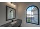 Modern bathroom with a stylish vanity, arched window offering natural light and an outdoor view at 23964 N 128Th Pl, Scottsdale, AZ 85255