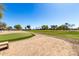 View of the lush putting green with landscaping and bench seating, a perfect spot for practicing your short game at 36579 W Barcelona Ln, Maricopa, AZ 85138
