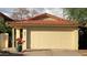 Attached garage with a red tile roof, a concrete driveway, and a blue planter with red flowers at 4335 E Monte Way, Phoenix, AZ 85044