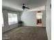 An open-concept living room with a ceiling fan, neutral carpet, and view of the kitchen at 4335 E Monte Way, Phoenix, AZ 85044