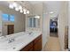 Bathroom featuring dual sinks, with a view of the walk-in closet at 4828 E Capistrano Ave, Phoenix, AZ 85044