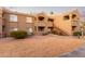 Tan stucco condo building featuring an exterior staircase and well-maintained landscaping at 5335 E Shea Blvd # 2102, Scottsdale, AZ 85254