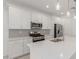 Bright kitchen featuring white cabinets, stainless steel appliances, a gray backsplash, and a large kitchen island at 5358 W Las Palmaritas Dr, Glendale, AZ 85302