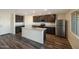 Modern kitchen featuring dark cabinets, stainless steel appliances, and a large center island with sink at 1057 W West Virginia Ave, Florence, AZ 85132