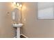 Cozy powder room with neutral walls, pedestal sink, decorative mirror, and laminate flooring for easy maintenance at 10938 W Pierson St, Phoenix, AZ 85037