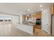 An open kitchen features an island with granite countertops, stainless steel appliances, and natural wood cabinetry at 13769 W Whisper Rock Trl, Peoria, AZ 85383
