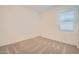 A bedroom features neutral carpet and white walls, brightened by natural light from a window at 15032 W Gray Fox Trl, Surprise, AZ 85387