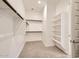 Bright, carpeted walk-in closet with custom shelves and hanging rods for organization at 15032 W Gray Fox Trl, Surprise, AZ 85387