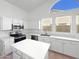 Well-lit kitchen with a center island, white cabinets, stainless steel appliances, and bright white countertops at 15420 S 29Th St, Phoenix, AZ 85048