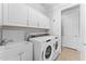 Well-organized laundry room featuring a washer, dryer, sink, white cabinetry, and tile flooring, offering practicality and style at 20408 E Rosa Rd, Queen Creek, AZ 85142