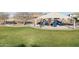 A community playground is equipped with colorful slides and climbing structures under a shaded canopy, surrounded by a grassy area at 20408 E Rosa Rd, Queen Creek, AZ 85142