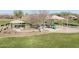 A community playground features a variety of play structures and shaded seating areas, bordered by well-maintained green spaces at 20408 E Rosa Rd, Queen Creek, AZ 85142