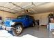 Spacious garage with a ladder, blue jeep, golf clubs, and overhead garage door at 2120 E Daley Ln, Phoenix, AZ 85024