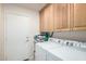 Laundry room with a Speed Queen washer and dryer and upper wood cabinets at 2120 E Daley Ln, Phoenix, AZ 85024