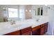 Well-lit bathroom with dual sinks, spacious mirrors, and attractive wood cabinetry at 25564 W Magnolia St, Buckeye, AZ 85326