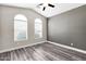 Comfortable bedroom with ceiling fan, wood-look flooring, and natural light from two windows at 647 E Palomino Way, San Tan Valley, AZ 85143