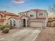 A charming two-story home with a red tile roof, stucco exterior, arched windows, desert landscaping and an attached two-car garage at 647 E Palomino Way, San Tan Valley, AZ 85143