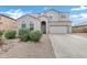 A charming two-story home with a red tile roof, stucco exterior, arched windows, desert landscaping and an attached two-car garage at 647 E Palomino Way, San Tan Valley, AZ 85143