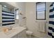 Clean bathroom featuring a single vanity, a full mirror, and a shower with a blue and white striped curtain at 10839 W Lincoln St, Avondale, AZ 85323