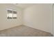 Minimalist bedroom with a window, offering a serene and uncluttered space with neutral tones and plush carpeting at 12738 N 172Nd Dr, Surprise, AZ 85388