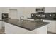 Modern kitchen island with dark countertops, white cabinets, stainless steel appliances, and hexagon backsplash at 12738 N 172Nd Dr, Surprise, AZ 85388