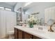 Bathroom featuring double sinks, wooden cabinets, large mirror and tasteful decor creating a serene and functional space at 12873 N 175Th Dr, Surprise, AZ 85388