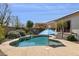 Backyard kidney-shaped pool surrounded by desert landscaping and a concrete patio with a blue umbrella at 12873 N 175Th Dr, Surprise, AZ 85388