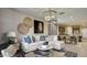 Bright living room features a large white couch, stylish decor, and an open concept design leading to the kitchen at 1333 S 239Th Dr, Buckeye, AZ 85326