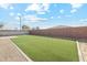 An artificial grass backyard with a gravel area, a brick-lined border, and a privacy wall at 18153 W Fulton St, Goodyear, AZ 85338