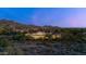 Twilight aerial view of a sprawling estate surrounded by desert landscape and mountains, showcasing luxury living at 19494 N 98Th Pl, Scottsdale, AZ 85255