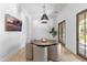 Dining area with a round wood table, six upholstered chairs, modern light fixtures, and decorative wall paneling at 19494 N 98Th Pl, Scottsdale, AZ 85255