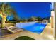 A luxurious backyard featuring a pool with water feature, sun bathing chairs and mature desert vegetation at 19494 N 98Th Pl, Scottsdale, AZ 85255