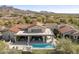 Aerial shot of the backyard showcasing the pool, patio, and lush landscaping against mountain views at 19494 N 98Th Pl, Scottsdale, AZ 85255