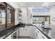 Elegant wet bar featuring white cabinets, a dark countertop, ample storage, and views of the outdoor scenery at 19494 N 98Th Pl, Scottsdale, AZ 85255