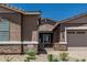 Front exterior view of the house, featuring desert landscaping, a brick facade, and a two-car garage at 20624 S 216Th Pl, Queen Creek, AZ 85142