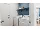 Efficient laundry room with washer, dryer, shelving, and a fresh blue accent wall at 23997 W Cocopah St, Buckeye, AZ 85326