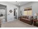Living room featuring neutral walls, carpet flooring, a leather sofa, a side table, a window, and access to the bathroom at 26648 W Quail Ave, Buckeye, AZ 85396