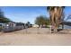 View of a fenced-in backyard with desert landscaping and a gray home with solar panels at 606 E Baseline Rd, Buckeye, AZ 85326