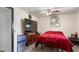 Cozy bedroom features dark red bedding, ceiling fan, and sleek entertainment center at 606 E Baseline Rd, Buckeye, AZ 85326