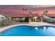 Resort-style backyard with a sparkling pool, lush greenery, patio, and sunset sky at 9014 E Sharon Dr, Scottsdale, AZ 85260