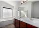 Bathroom featuring double sinks, wood cabinets, and a tub under a window with lots of natural light at 911 E Lovegrass Dr, San Tan Valley, AZ 85143