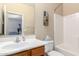 A well-lit bathroom with wood cabinets, a sink, and a toilet with a bathtub at 1015 S Val Vista Dr # 81, Mesa, AZ 85204