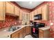 A kitchen with wooden cabinets, black appliances, and bright floral wallpaper at 1015 S Val Vista Dr # 81, Mesa, AZ 85204