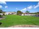 Expansive front yard featuring lush green grass, mature trees, a sport court, and a well-maintained white-walled exterior at 10541 E Windrose Dr, Scottsdale, AZ 85259