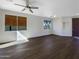 Spacious living room featuring wood floors, a ceiling fan, and windows to the front yard at 1131 E Catino St, San Tan Valley, AZ 85140