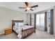 Comfortable bedroom features a wood frame bed, ceiling fan, and natural light from large windows at 1236 E Mescal St, Phoenix, AZ 85020