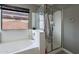 Modern bathroom with shower stall and soaking tub next to a bright window at 13547 W Peck Dr, Litchfield Park, AZ 85340