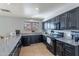 Functional kitchen features dark cabinets, tile flooring, granite countertops, and a window at 13547 W Peck Dr, Litchfield Park, AZ 85340